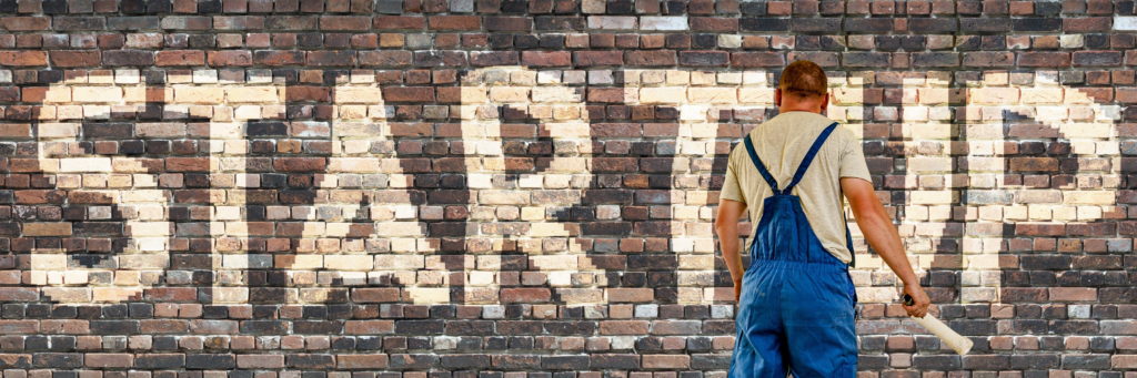 Painter paints Startup on brick wall